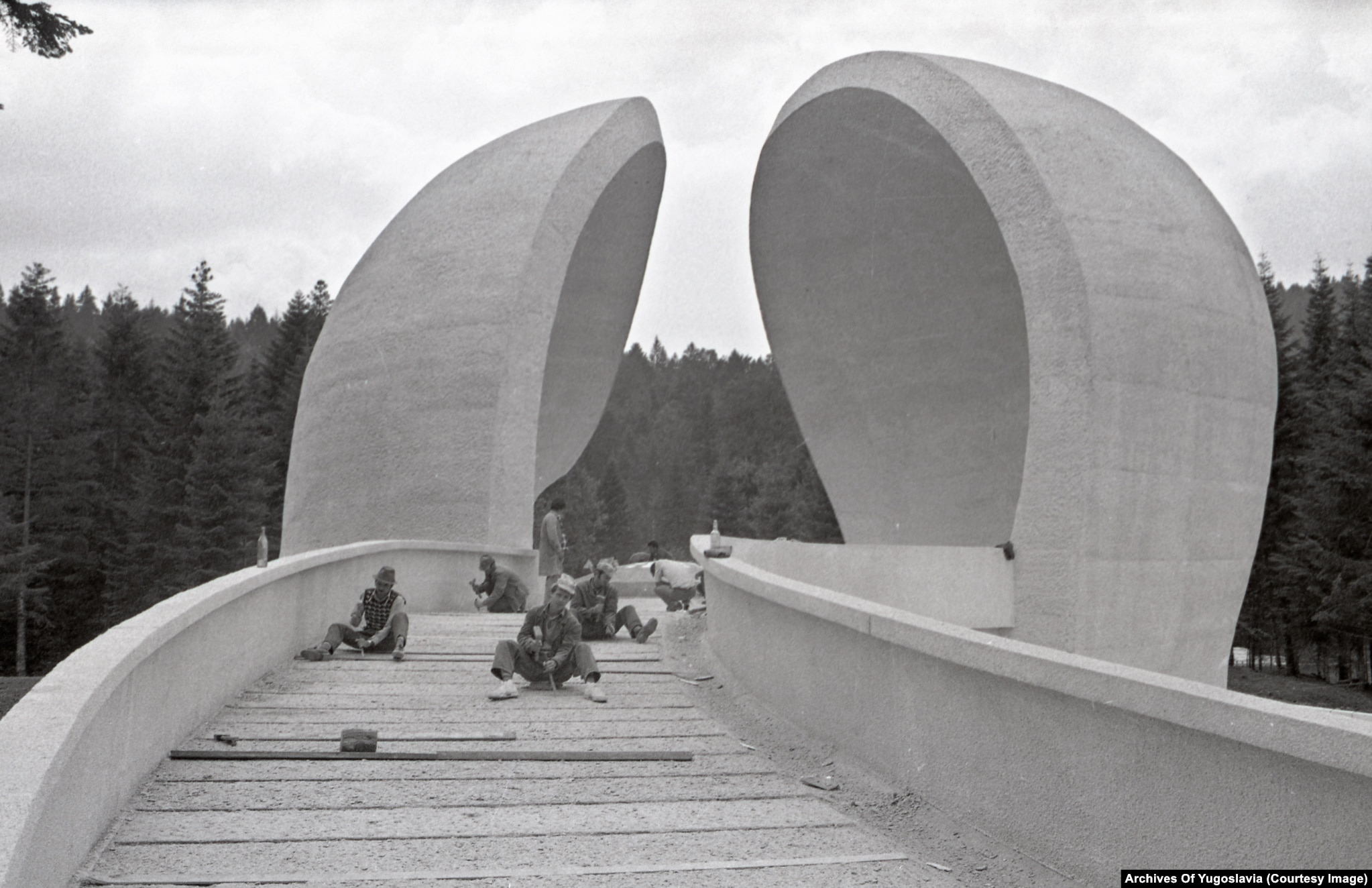 Bauarbeiter mit Werkzeug auf einem gepflasterten Zugangsweg am Grmeč-Krankenhausdenkmal, 1979.