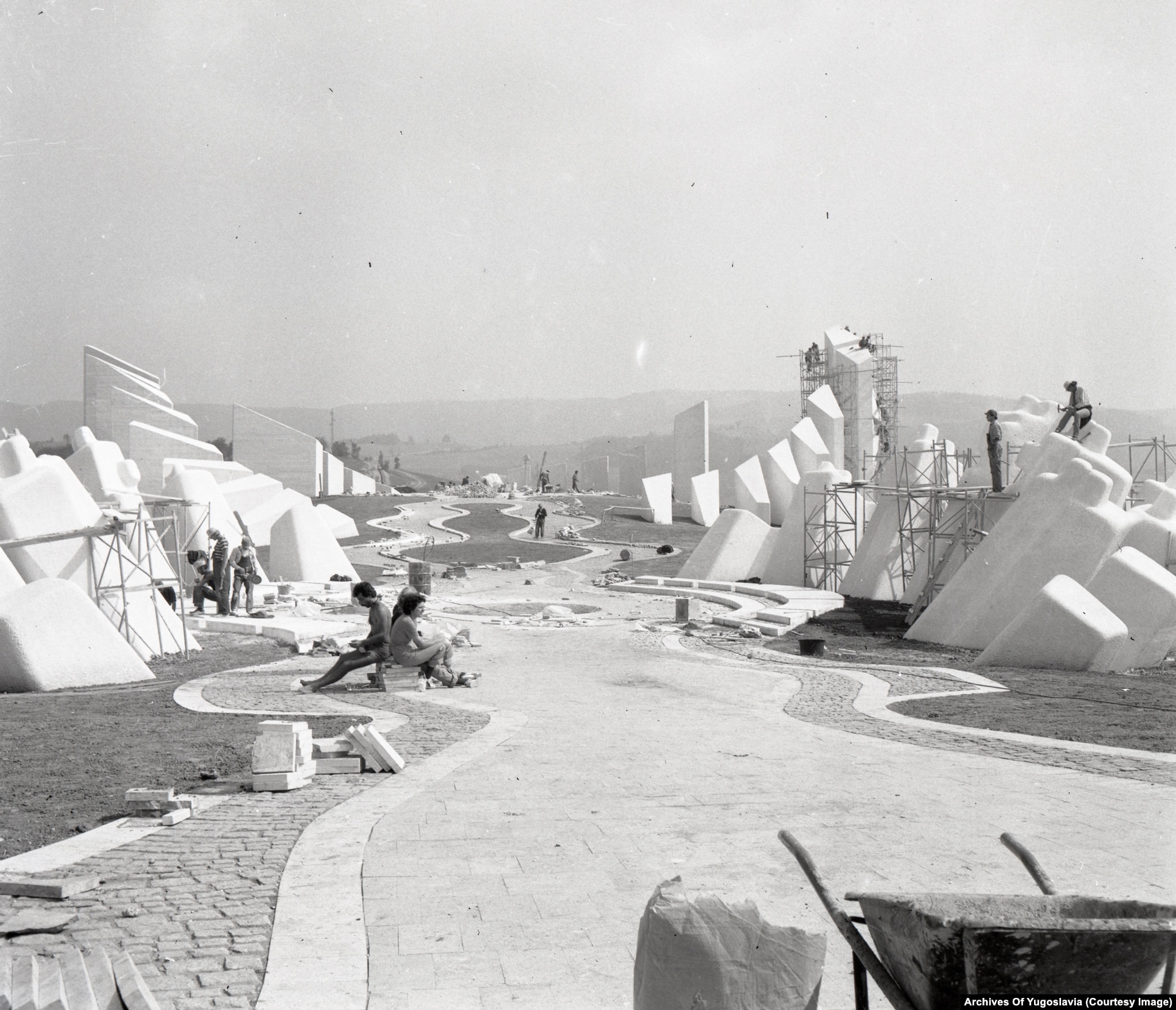 Schwarzweißfoto von Kränen und unfertigen Betonformen auf einem bewaldeten Hügel, Kadinjača, 1979.